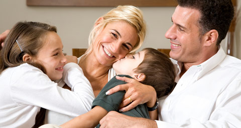 A mother and father cuddling their children